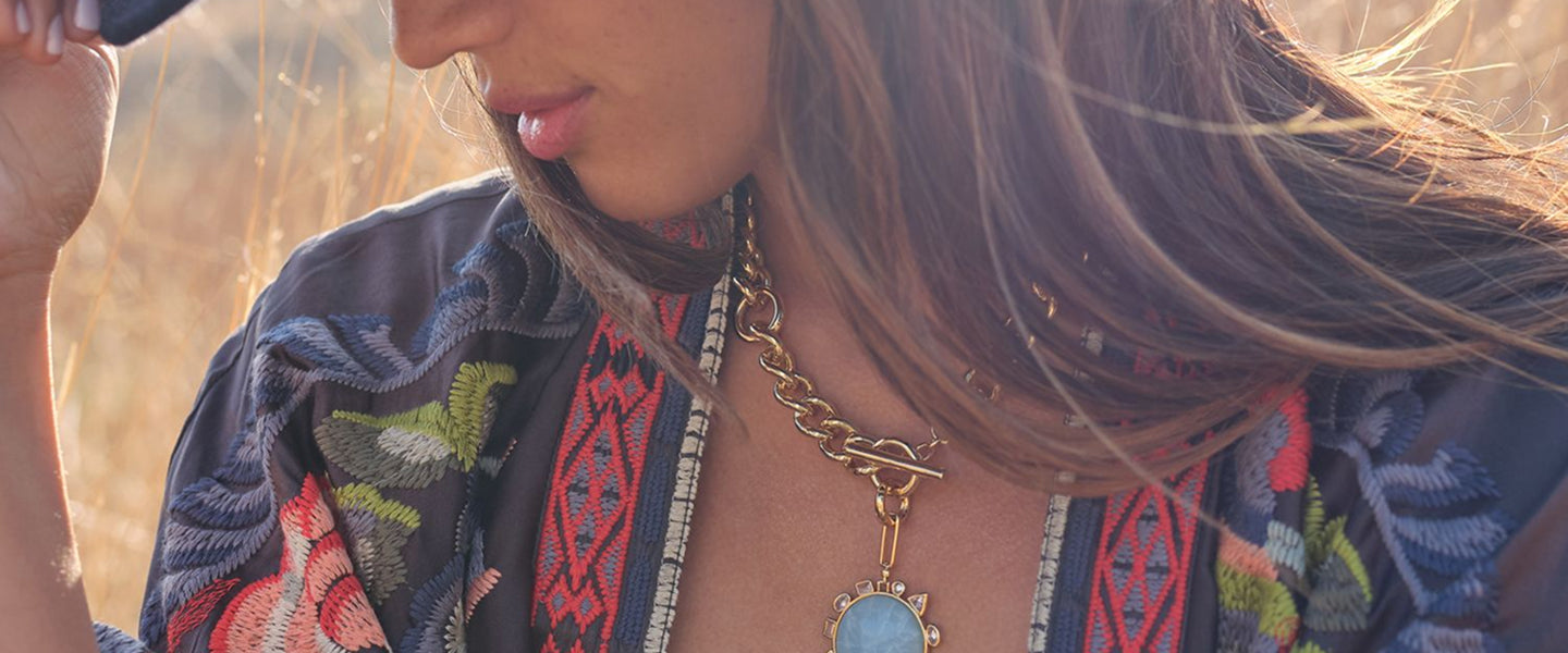 Woman wearing a colorful embroidered jacket with a necklace in a natural setting