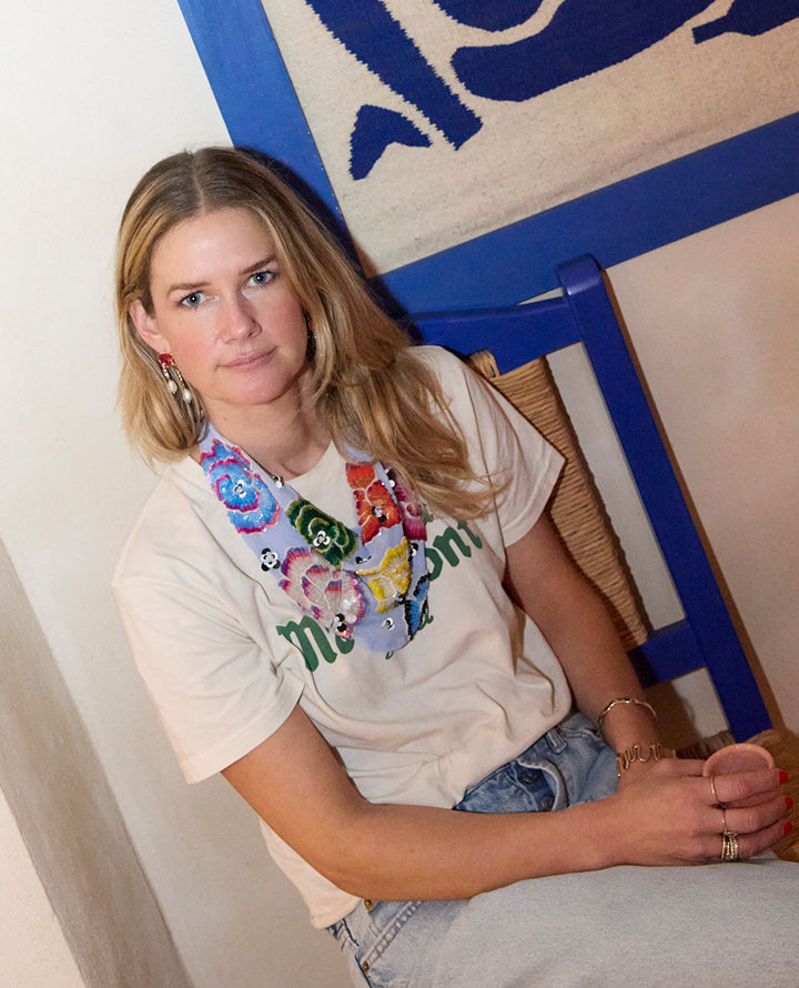 Woman sitting on a chair wearing a colorful graphic t-shirt with text.