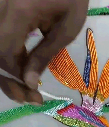 Hand beading a colorful design on fabric