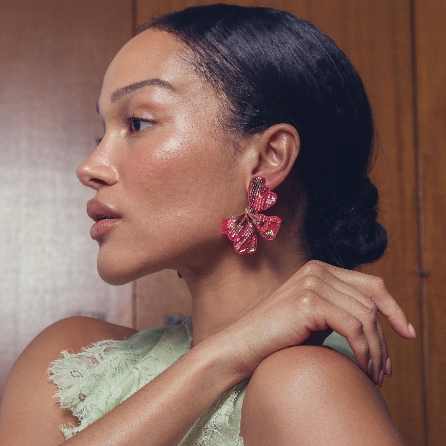 Woman wearing pink flower-shaped earrings with a neutral background