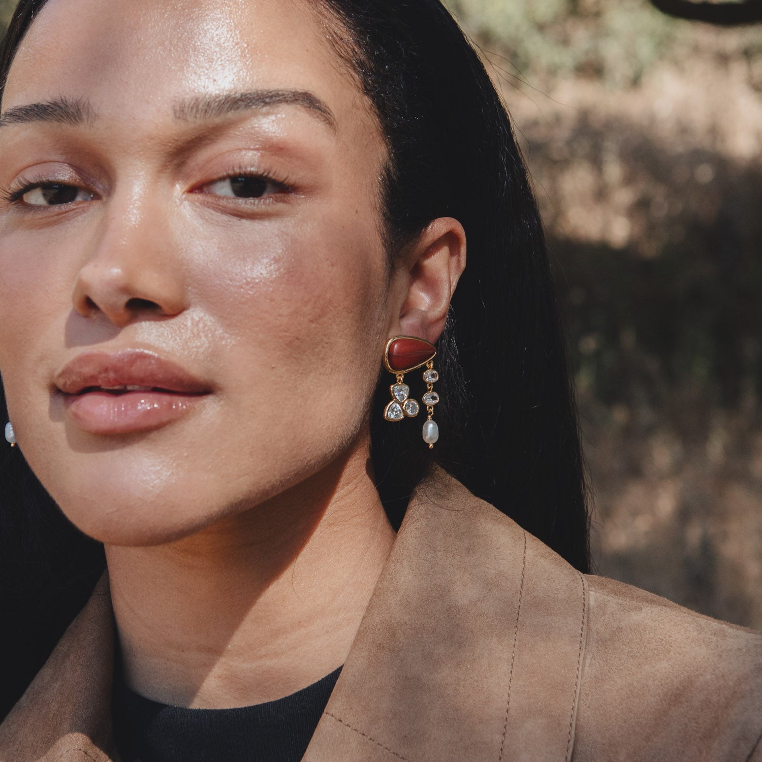 Close-up of a person wearing a red earring outdoors