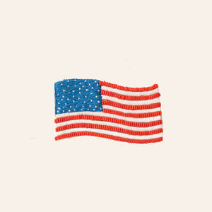 Beaded and Embroidered Red, White, and Blue American Flag Brooch on Tan Background