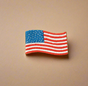 Beaded and Embroidered Red, White, and Blue American Flag Brooch on Tan Background