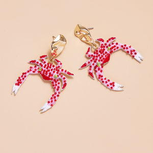 Red and White Beaded and Embroidered Crab Drop Earrings on Tan Background
