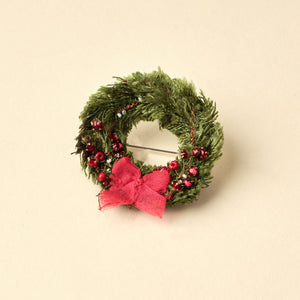 Green and Red Beaded and Embroidered Wreath Brooch on Tan Background