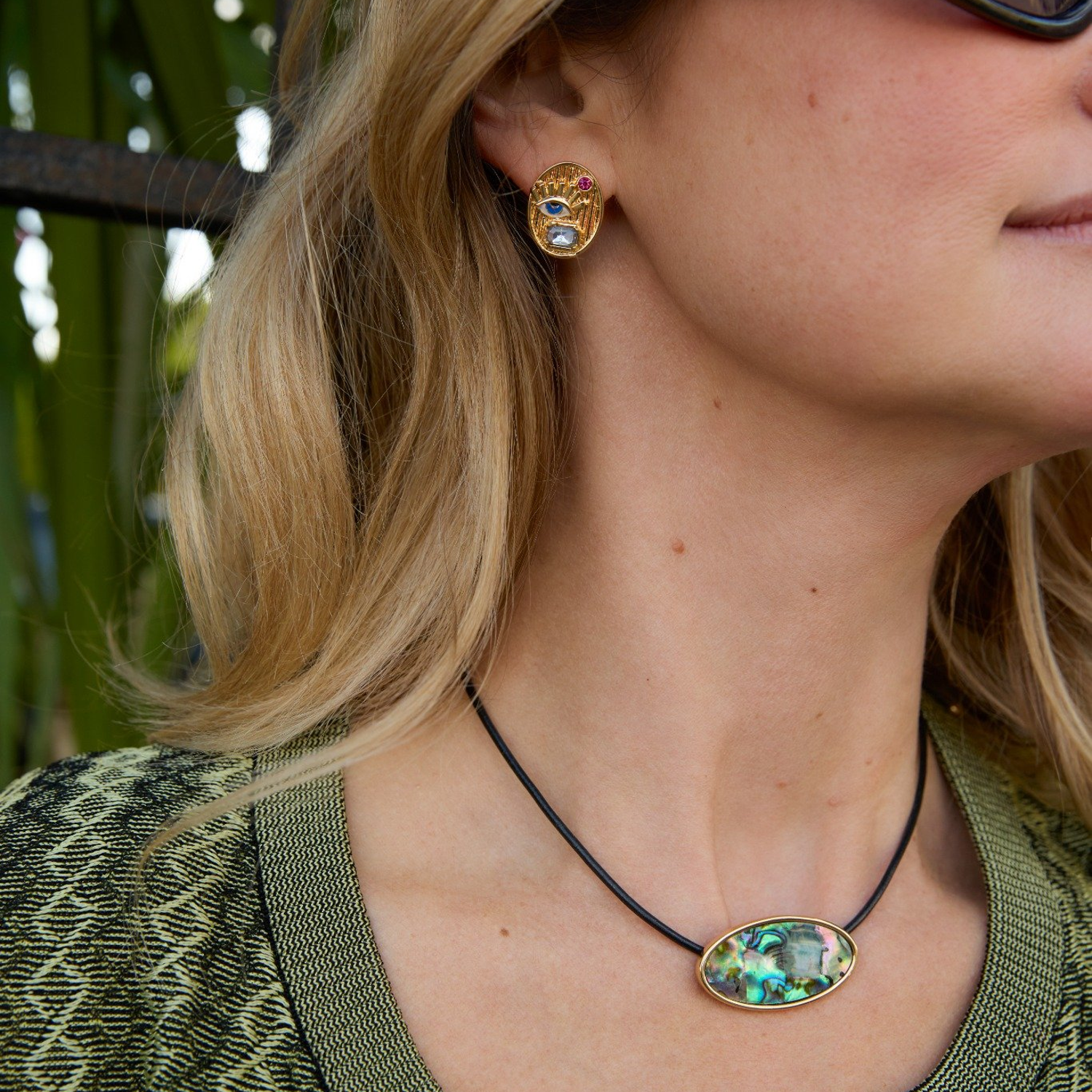 Model wearing gold studs and green cord necklace 