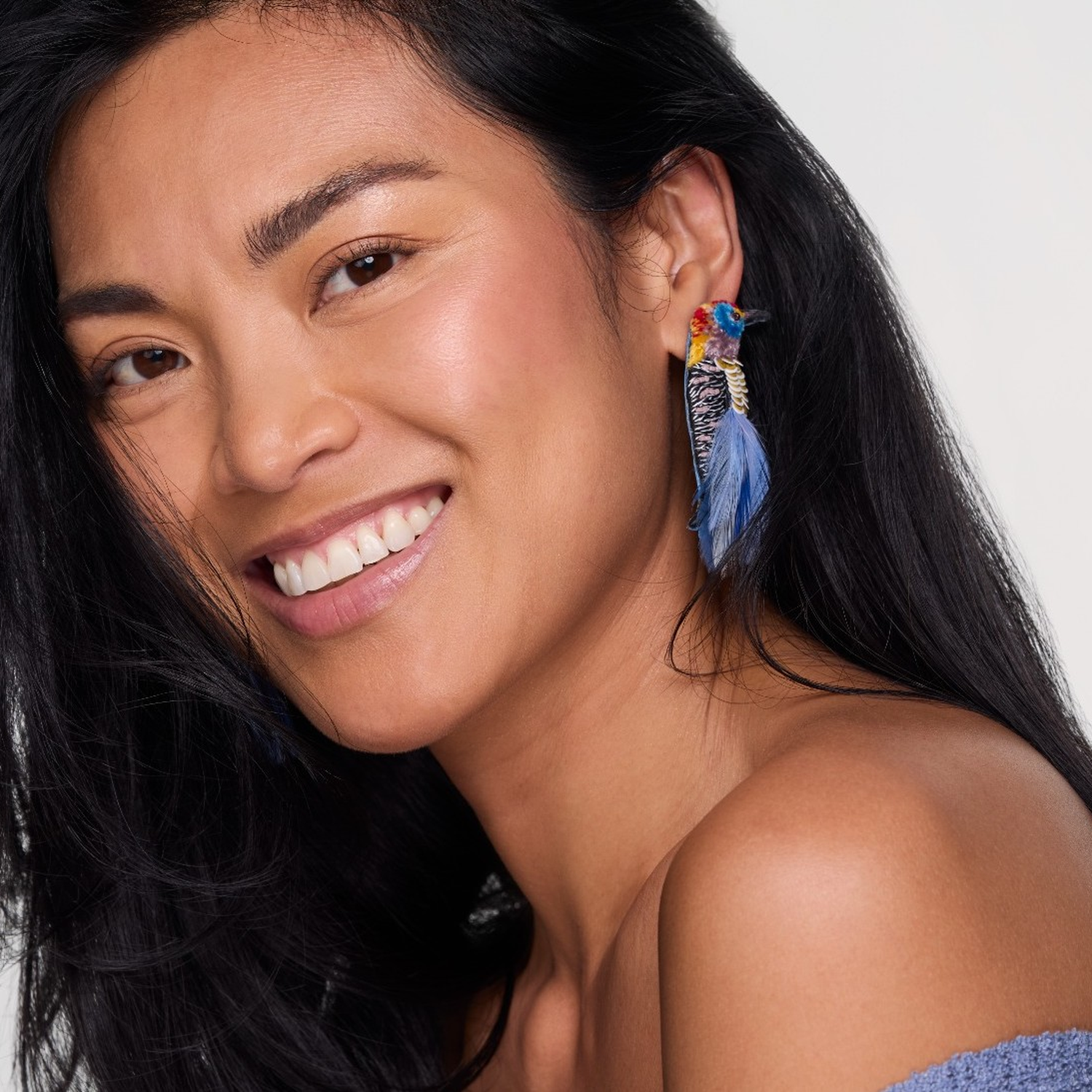 Woman wearing colorful earrings with a neutral background