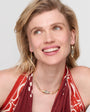 Woman wearing a red patterned top and gold jewelry against a white background
