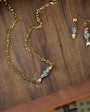 Gold necklace and earrings on a wooden surface