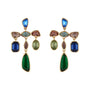 Colorful gold-tone statement earrings featuring blue, green, and clear faceted stones in a playful geometric design on white