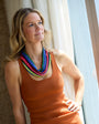 Woman wearing a colorful beaded bandana necklace indoors by a window