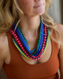 Woman wearing a colorful beaded necklace with a neutral background