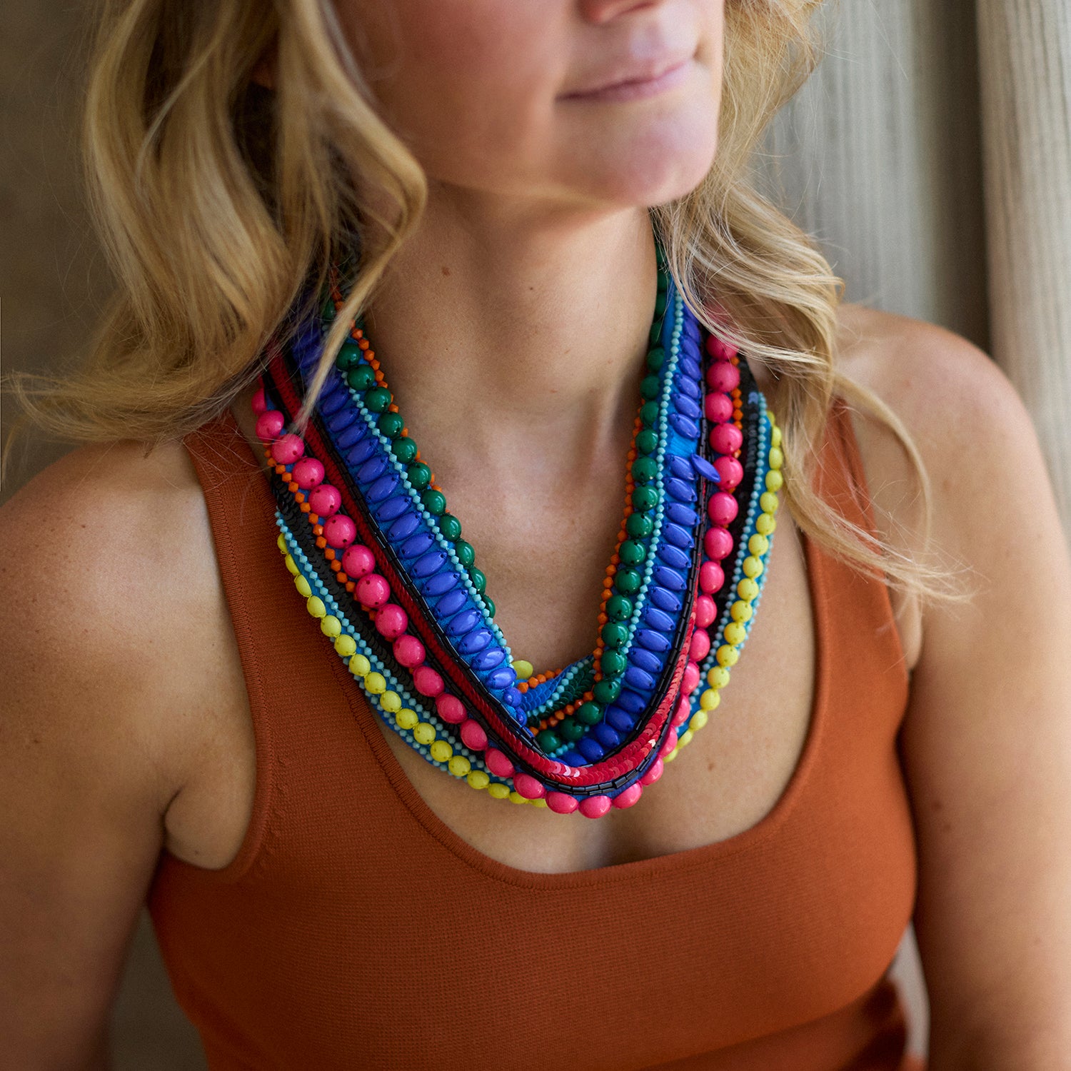 Woman wearing a colorful beaded necklace with a neutral background