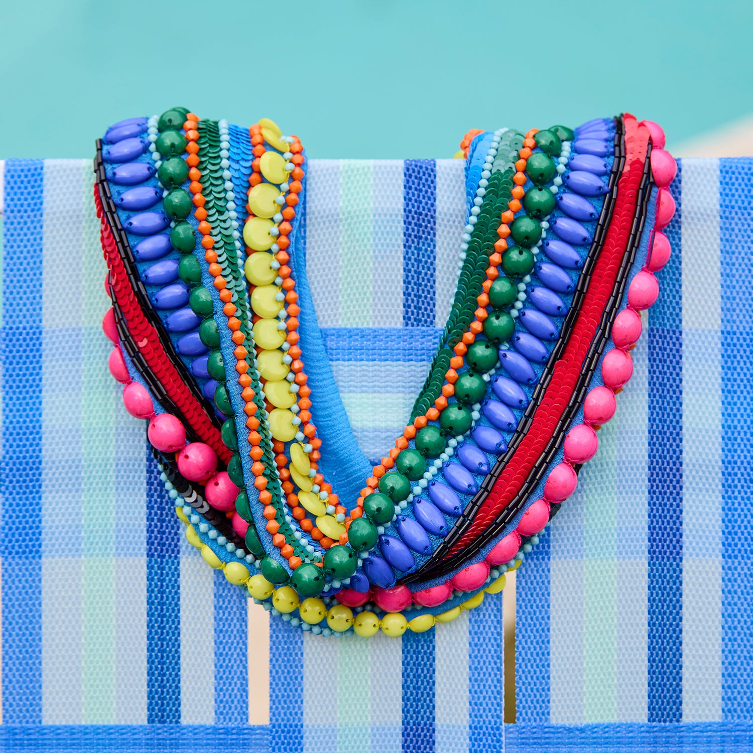 Colorful beaded necklace on a blue and white striped fabric background