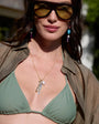 Woman wearing a green bikini top and sunglasses with a blurred background