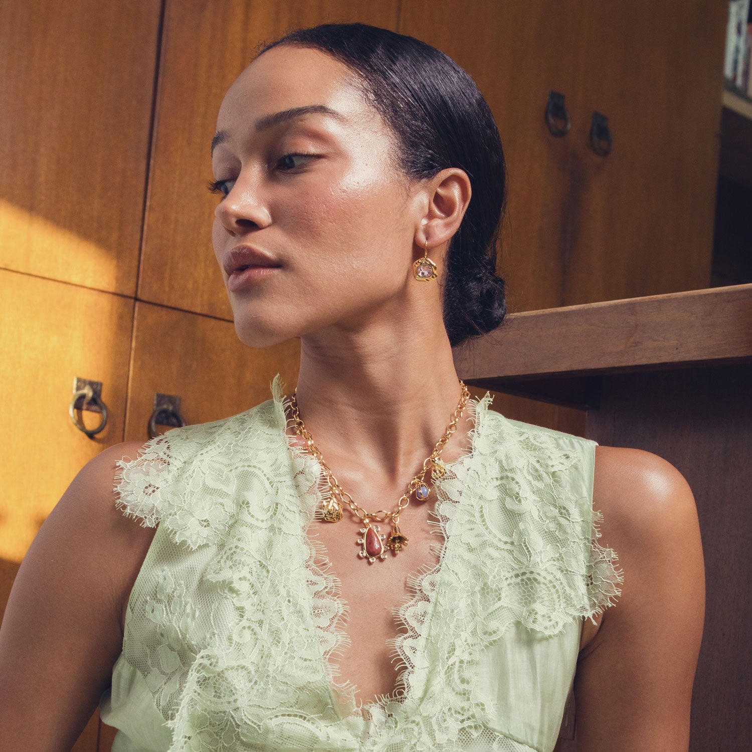 Gold charm necklace with semi-precious stones, pearls, and carnelian centerpiece styled on model