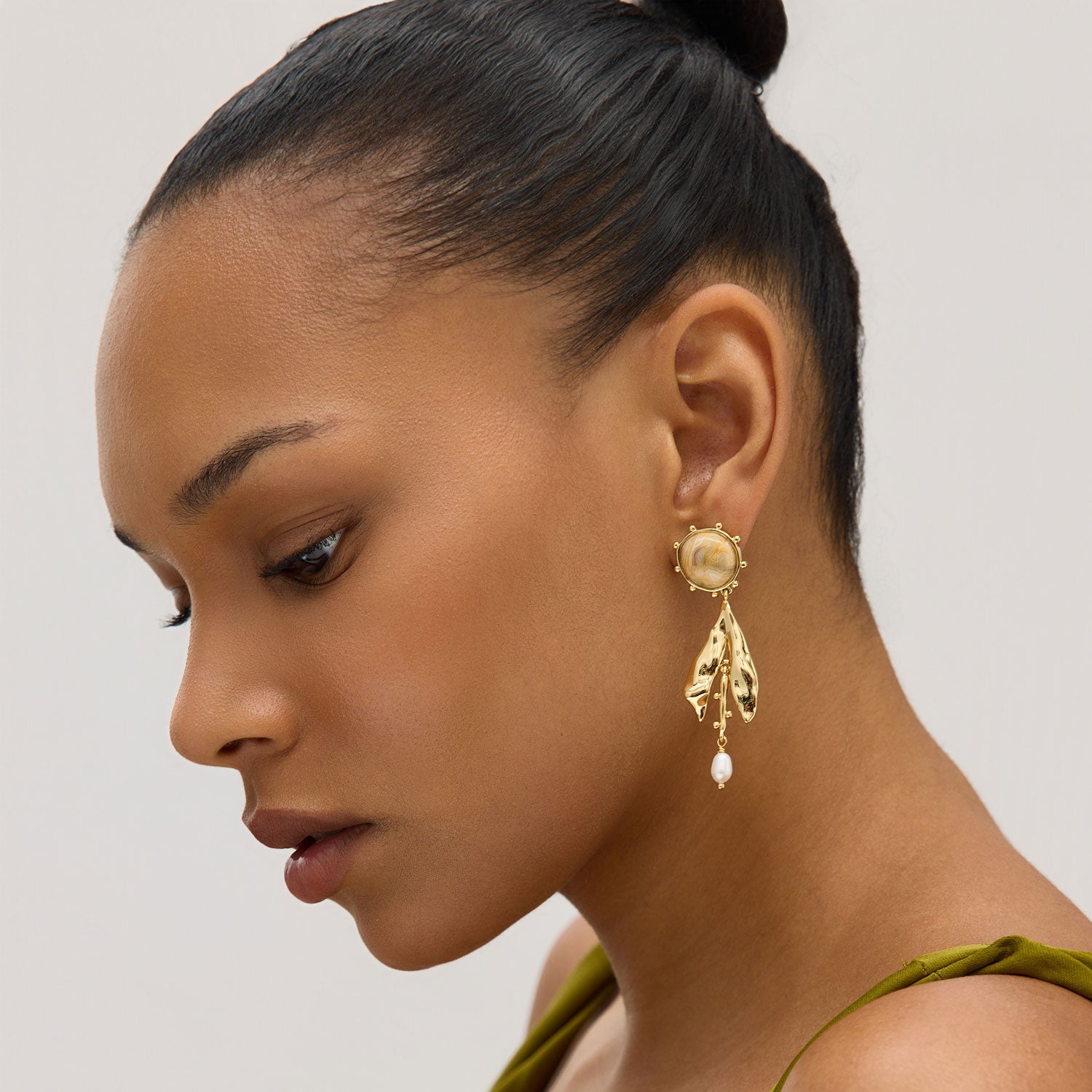 Woman wearing gold earrings with a plain background