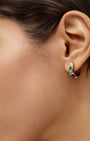 Close-up of a woman's ear wearing a colorful stone hoop earring.