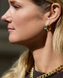 Maggie wearing stone and gold hoop earrings with blurred background