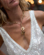 Close-up of a person wearing a gold necklace with a sequin top.