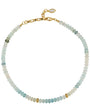 A beaded necklace made of small round beads that transition from light blue-green to pale green, white, and a few gold-toned beads, finished with a gold clasp and a small oval pendant, shown on a plain white background.