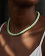 A light green beaded textured necklace around a models neck