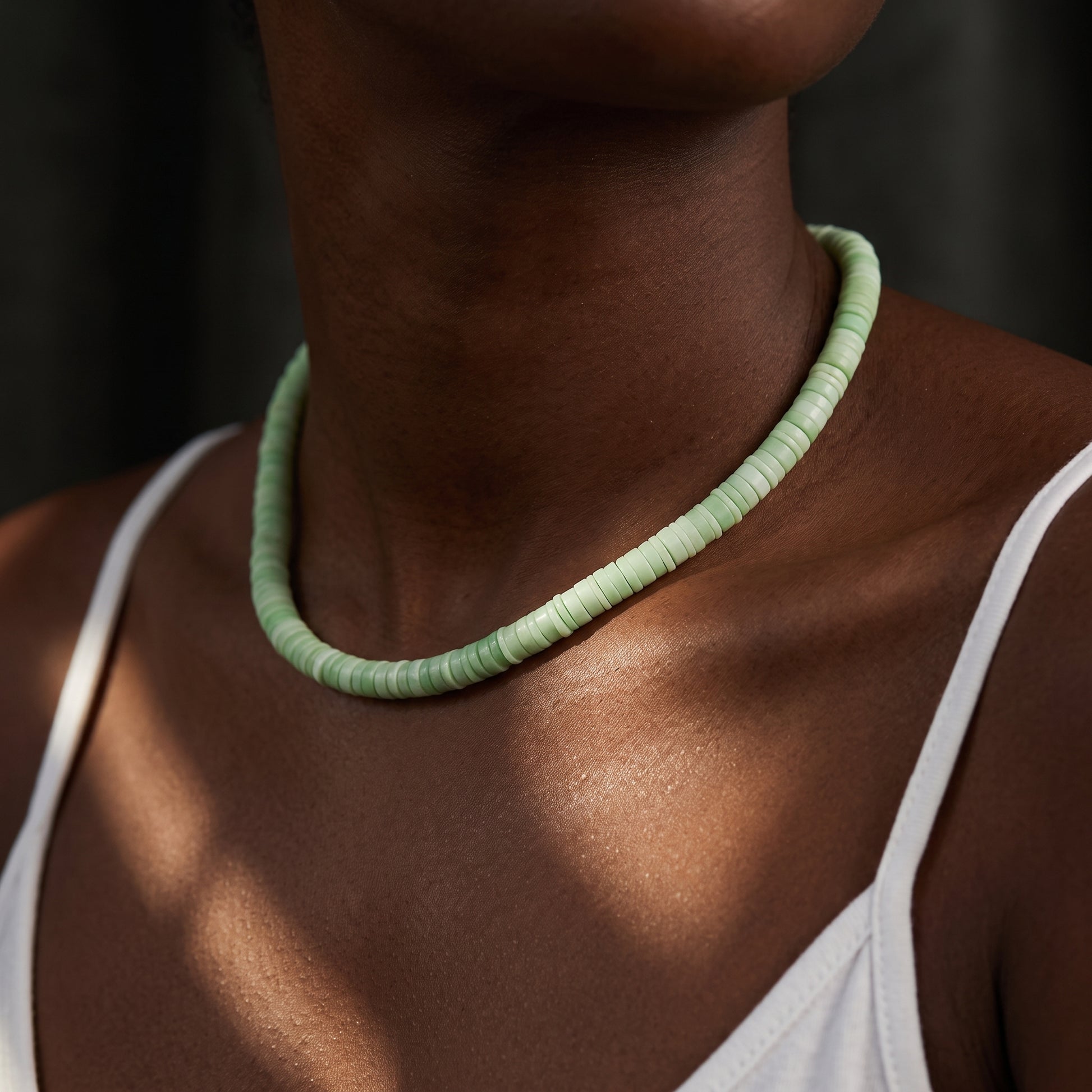A light green beaded textured necklace around a models neck