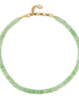 A delicate beaded necklace made of small, flat, light green disc-like beads, finished with a gold-tone clasp and extender chain.