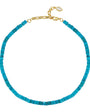 A turquoise beaded necklace with a gold clasp and a small white oval tag, displayed on a clean white background.