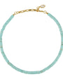 A beaded necklace made of small, flat, light turquoise-blue rectangular beads arranged in a circle, featuring a gold-tone chain extender with a teardrop-shaped white stone clasp, shown on a plain white background.