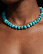 A close-up of a person wearing a turquoise beaded necklace, showing the beads against the skin.