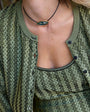 Person wearing a green patterned cardigan with a necklace.