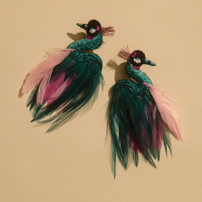 Teal and Pink Beaded and Feather Crane Bird Earrings Staged on Flat Cream Background