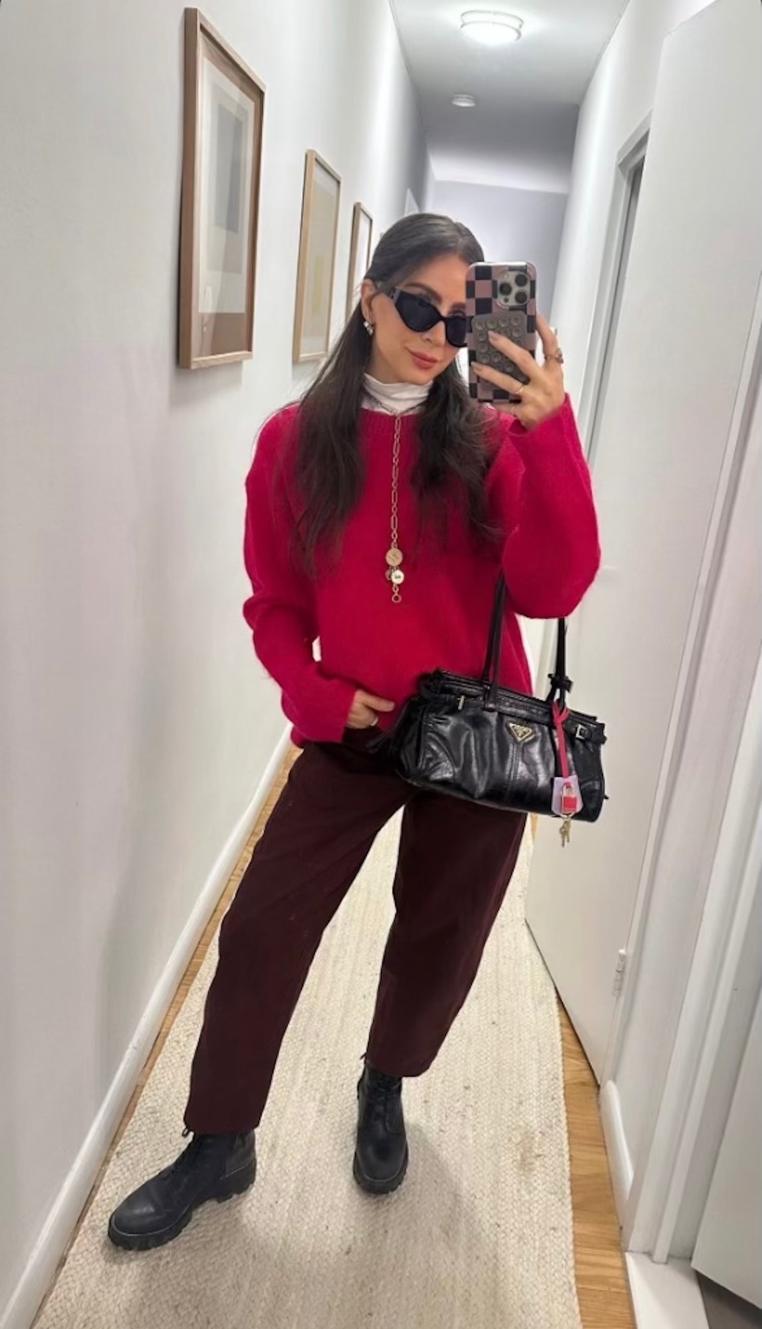 Model wearing red top and black pants with gold chain necklace 