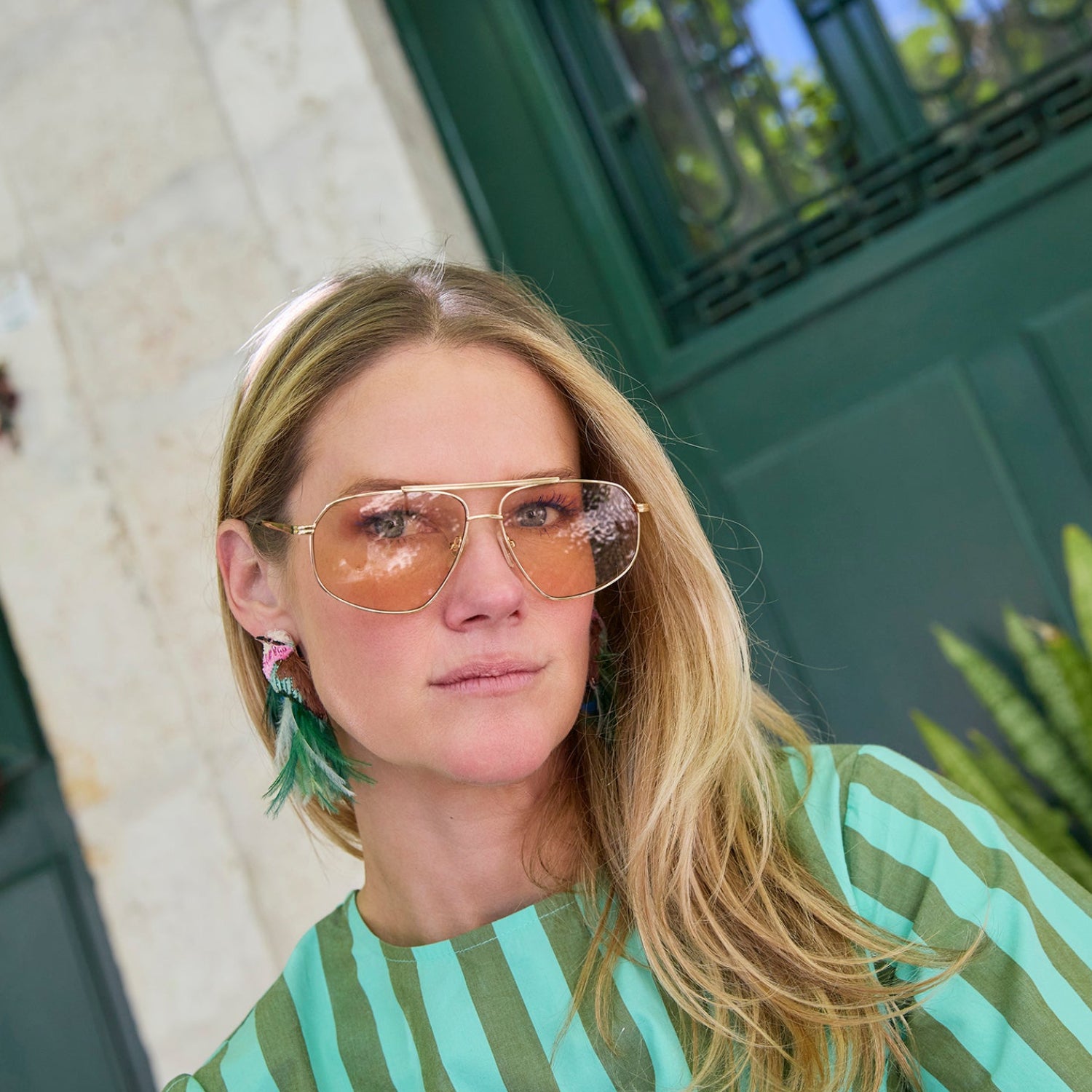 Model wearing bird embroidered statements earrings against city background