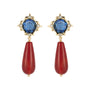A pair of gold drop earrings featuring a faceted blue gemstone in a starburst setting with small clear accent stones, and a long teardrop-shaped red bead dangling below.