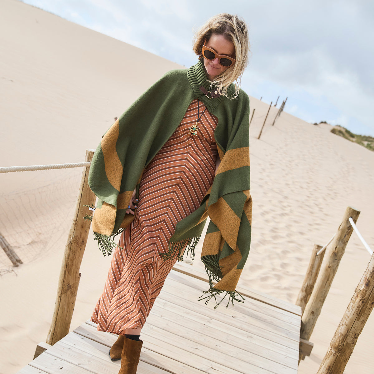 Model wearing a gold crescent moon pendant necklace with green and brown beads on a black cord, in a green sweater jacket