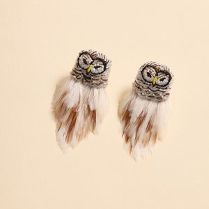 White and Brown Feather and Bead Owl Stud Earrings on Tan Background