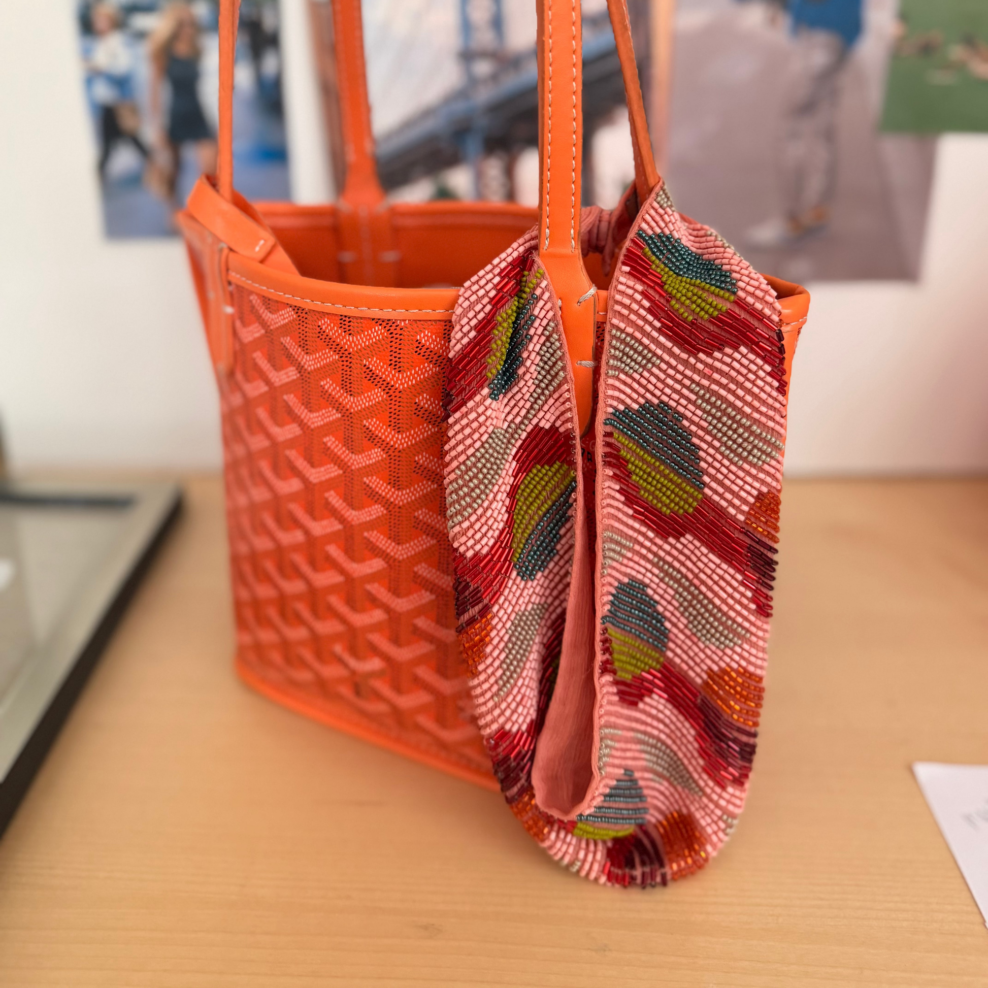 Orange woven handbag with a colorful scarf draped over it on a wooden surface.