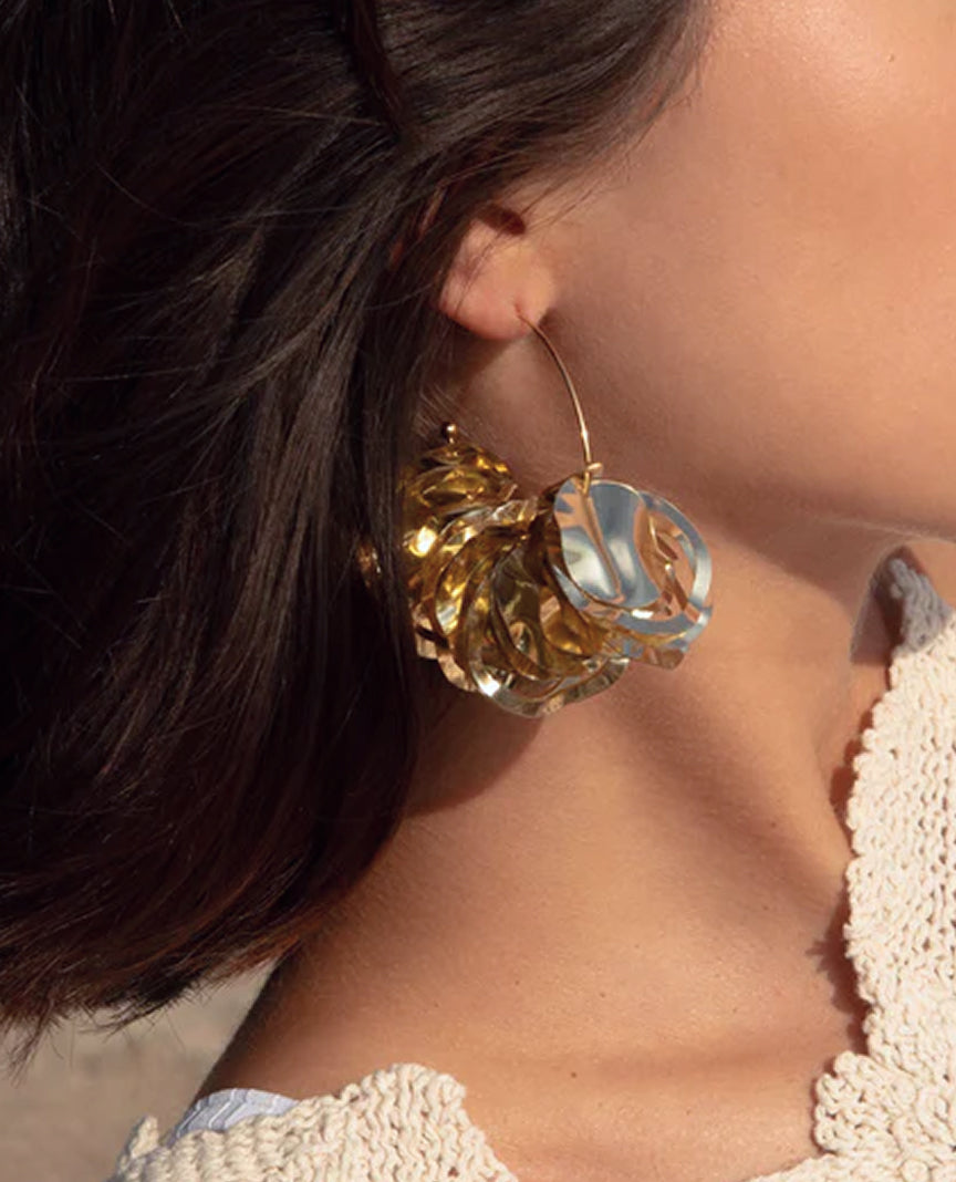Close up of large gold hoop earring with gold discs.