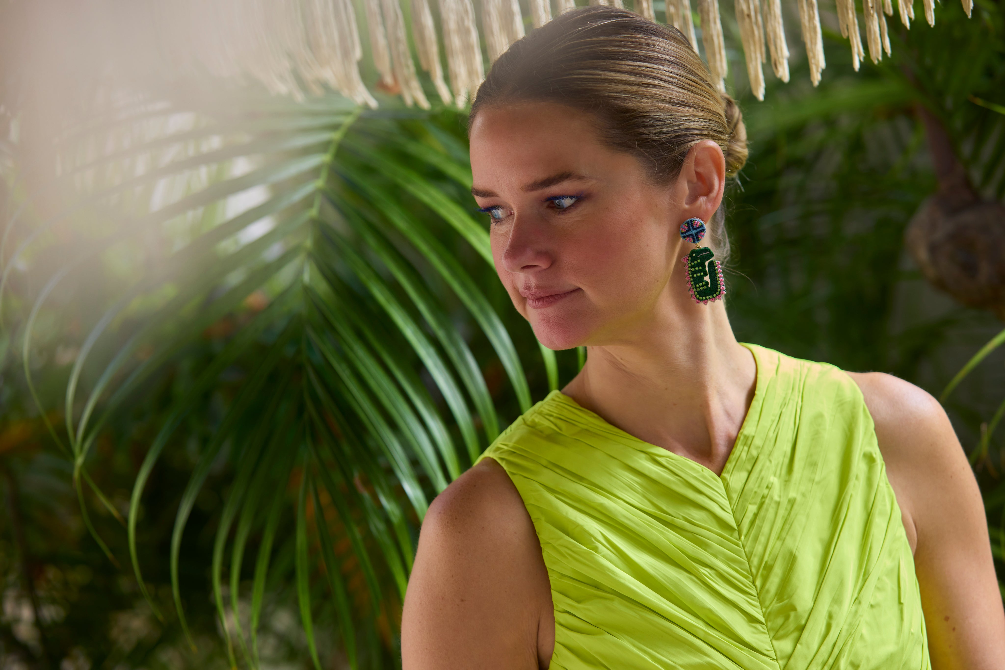 Woman wearing a green dress and earrings with a tropical background