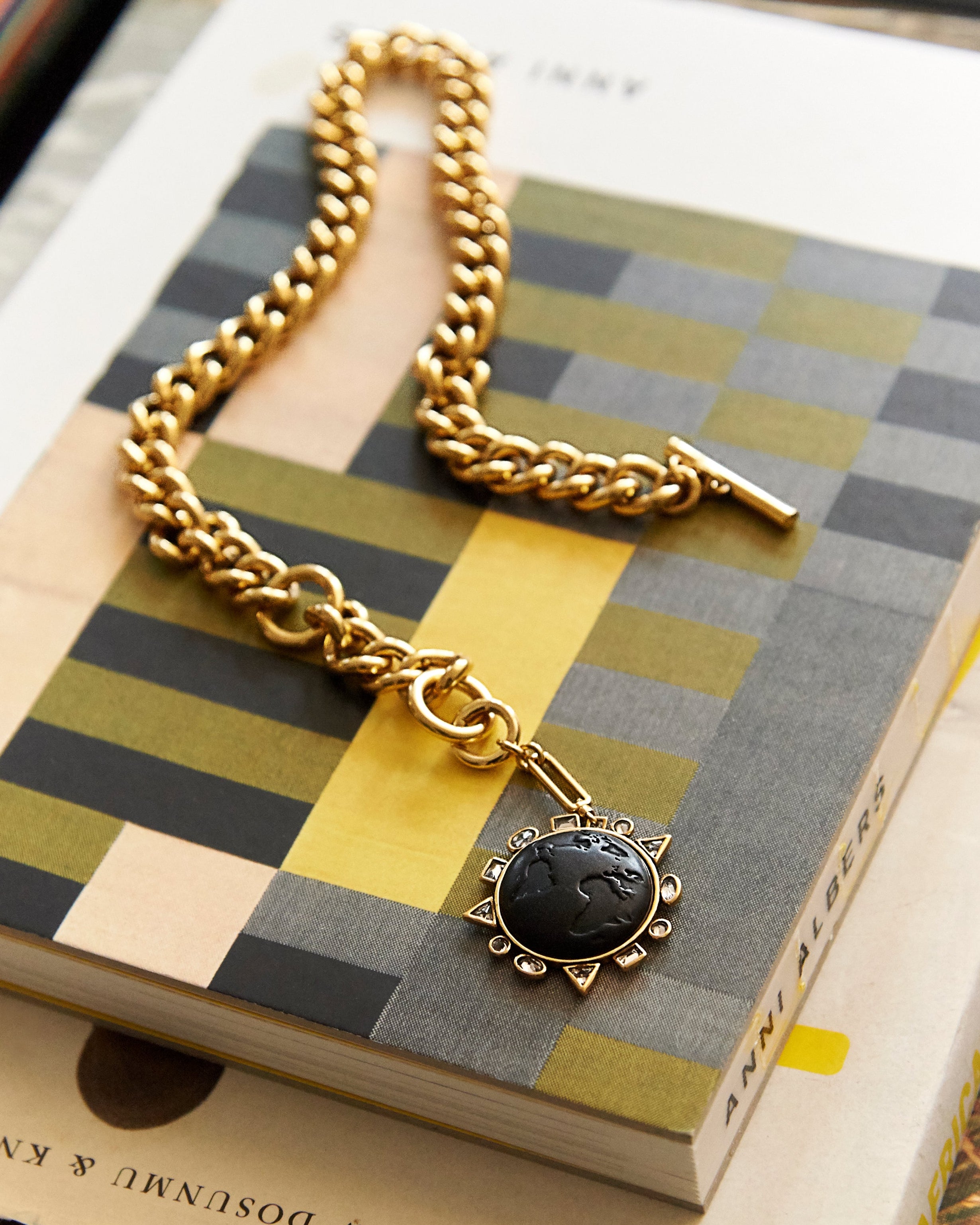 Gold chain necklace with a black pendant on a checkered book
