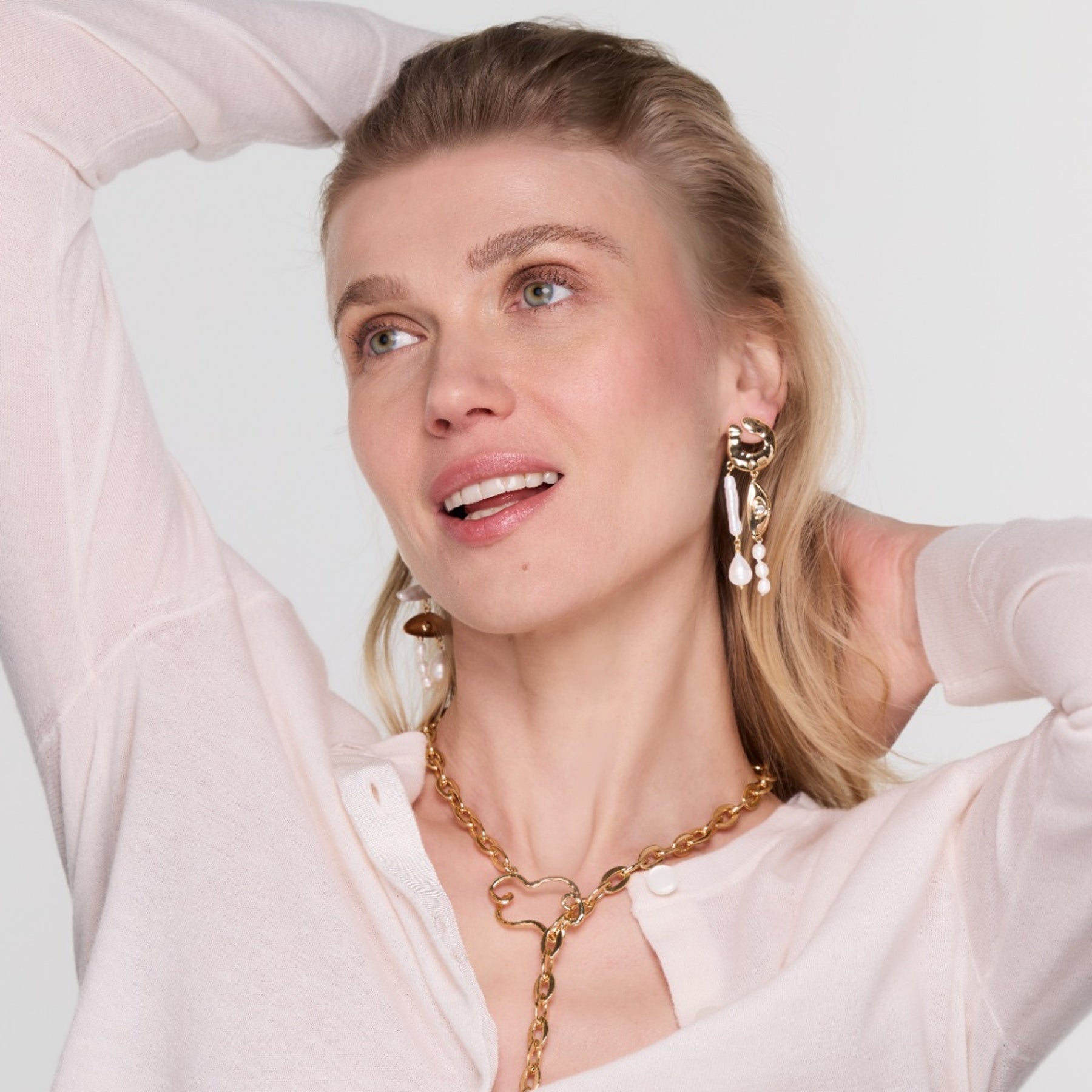 Woman wearing gold jewelry against a light background
