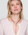 Woman wearing a gold necklace and earrings on a plain background