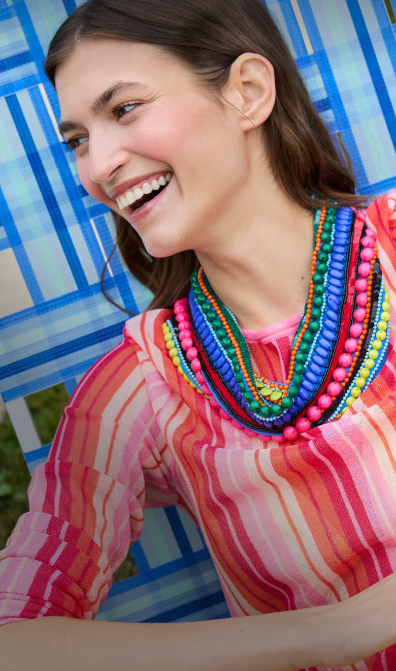 Woman wearing a colorful beaded necklace in front of a blue geometric patterned background