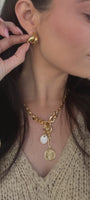 Video of model wearing gold chain necklace and gold hoop earrings