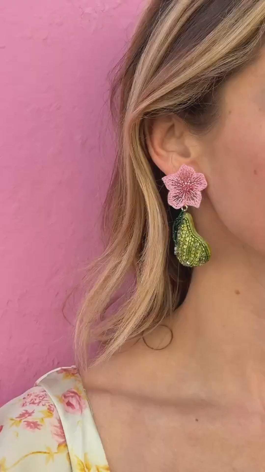 Model wearing pink and green pear shaped embroidered earrings against pink background