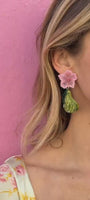Model wearing pink and green pear shaped embroidered earrings against pink background