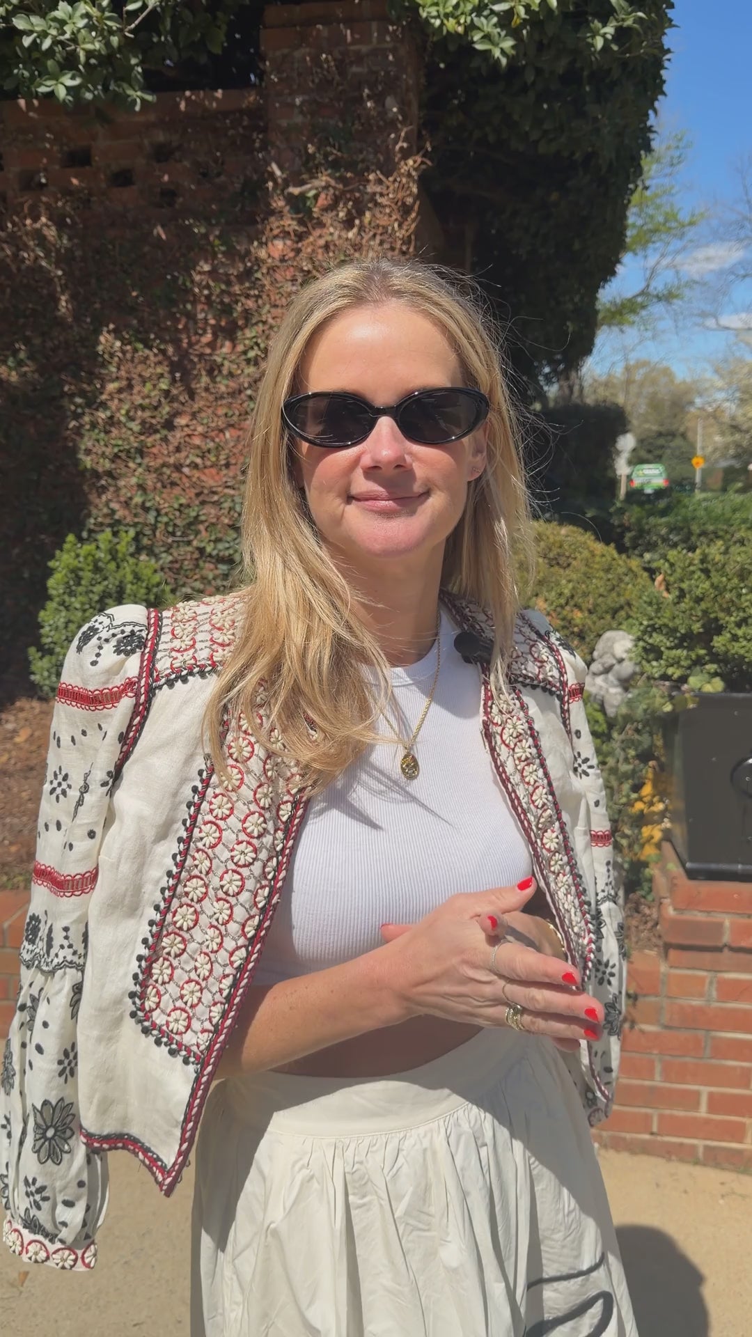 Model wearing white outfit with gold chain necklace featuring evil eye motif
