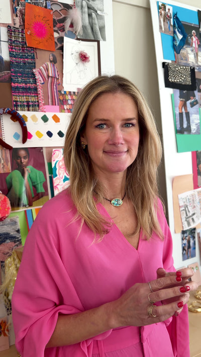 Model wearing pink top with gold stud earrings and iridescent green choker necklace